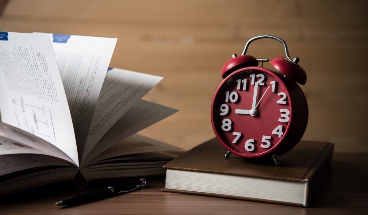 Books and alarm clock on wooden table. Education concept.